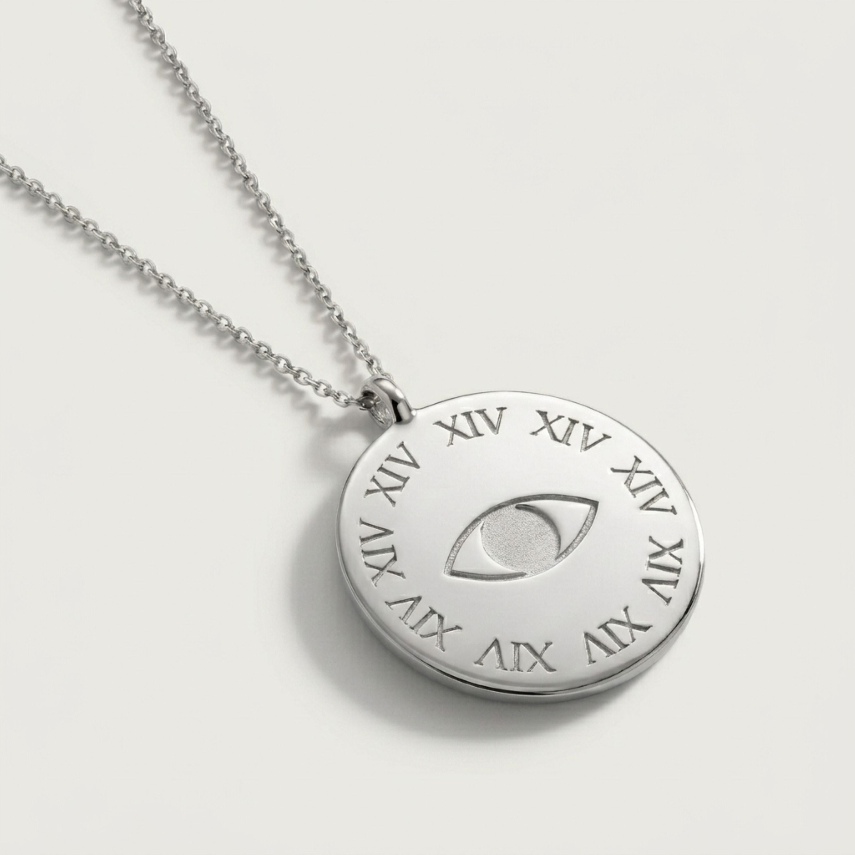 Silver necklace with a round pendant featuring Roman numerals and an eye symbol on a light gray background from Rachel's Worth