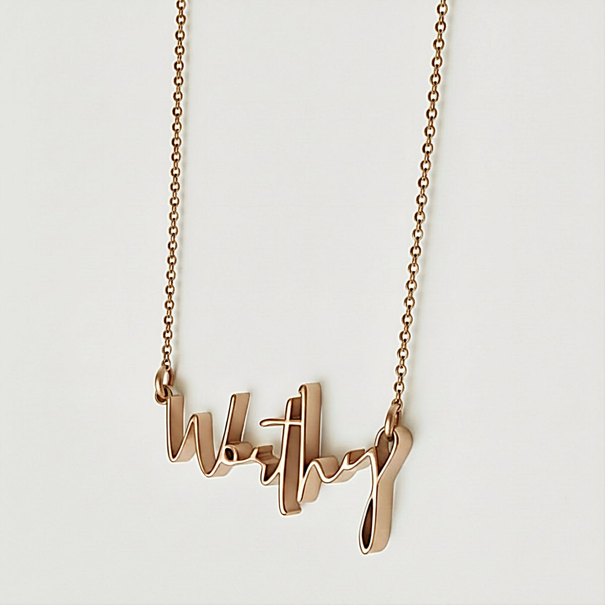 Close-up of the Worthy affirmation pendant highlighting its warm polished 18K rose gold vermeil finish.