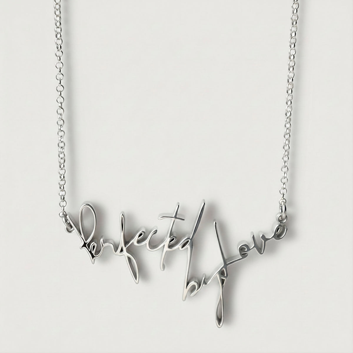 Front view of the Perfected by Love Sterling Silver Affirmation Necklace with its elongated statement pendant.