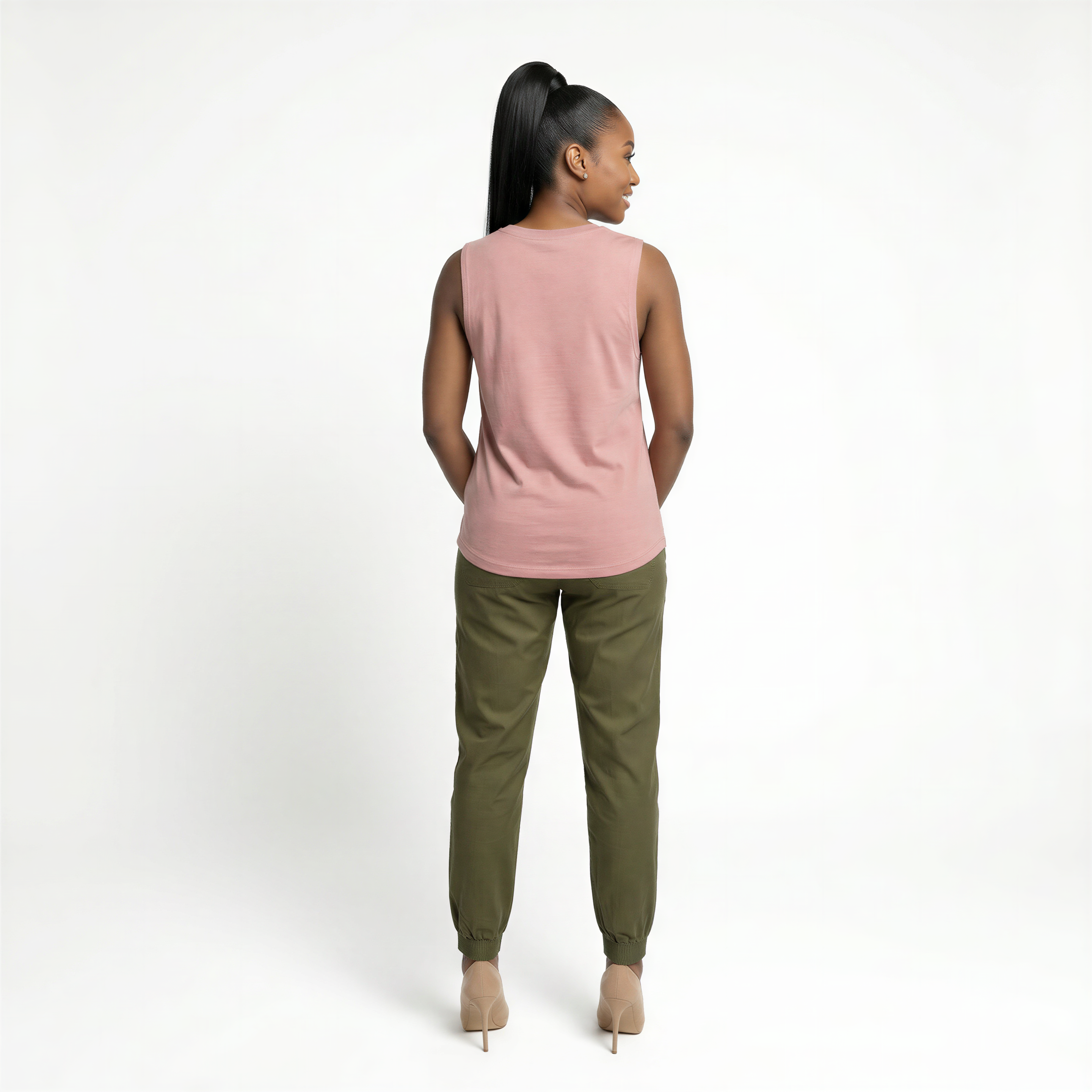 Woman wearing a pink sleeveless top and green pants on a white background