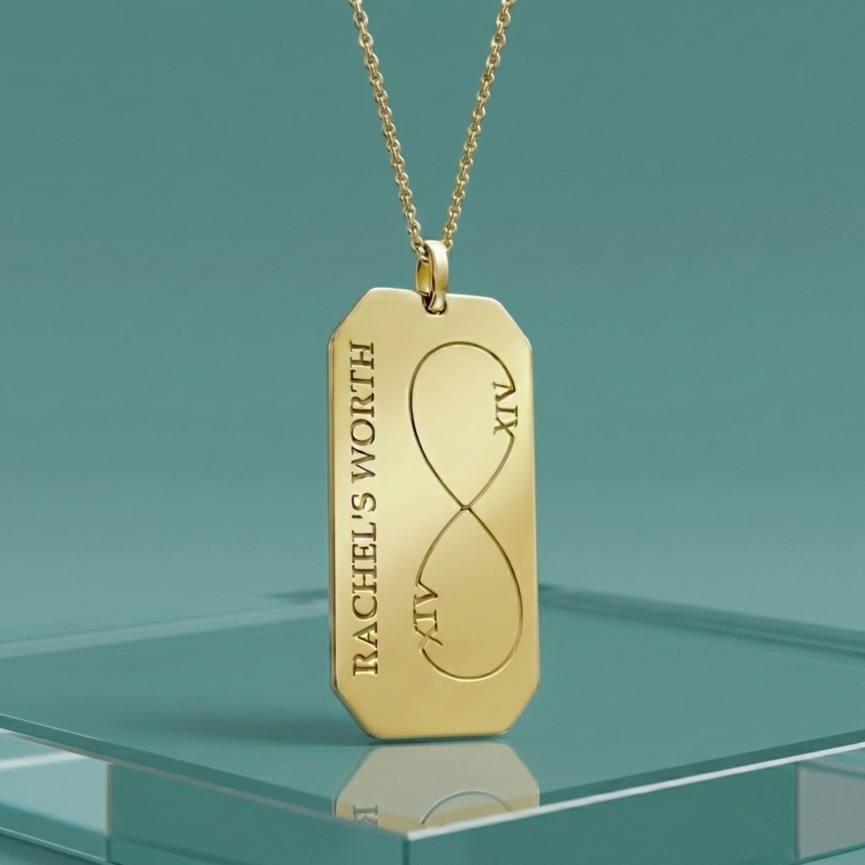 Gold pendant necklace with engraved text on a teal background
