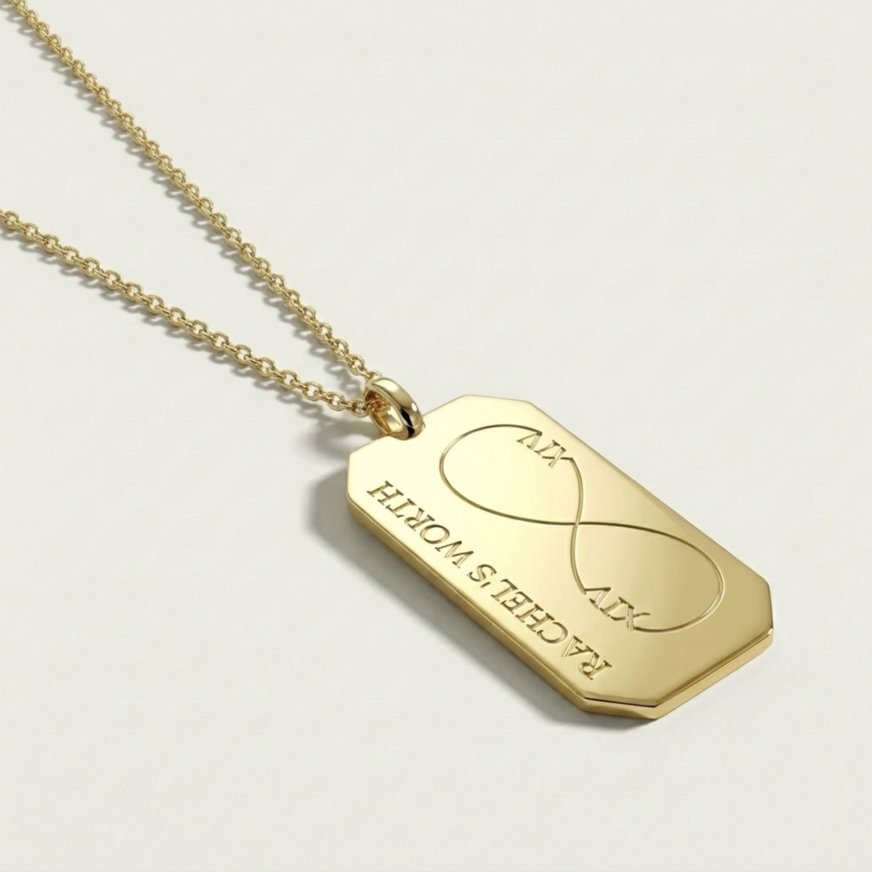 Gold necklace with a tag featuring an infinity symbol on a light gray background