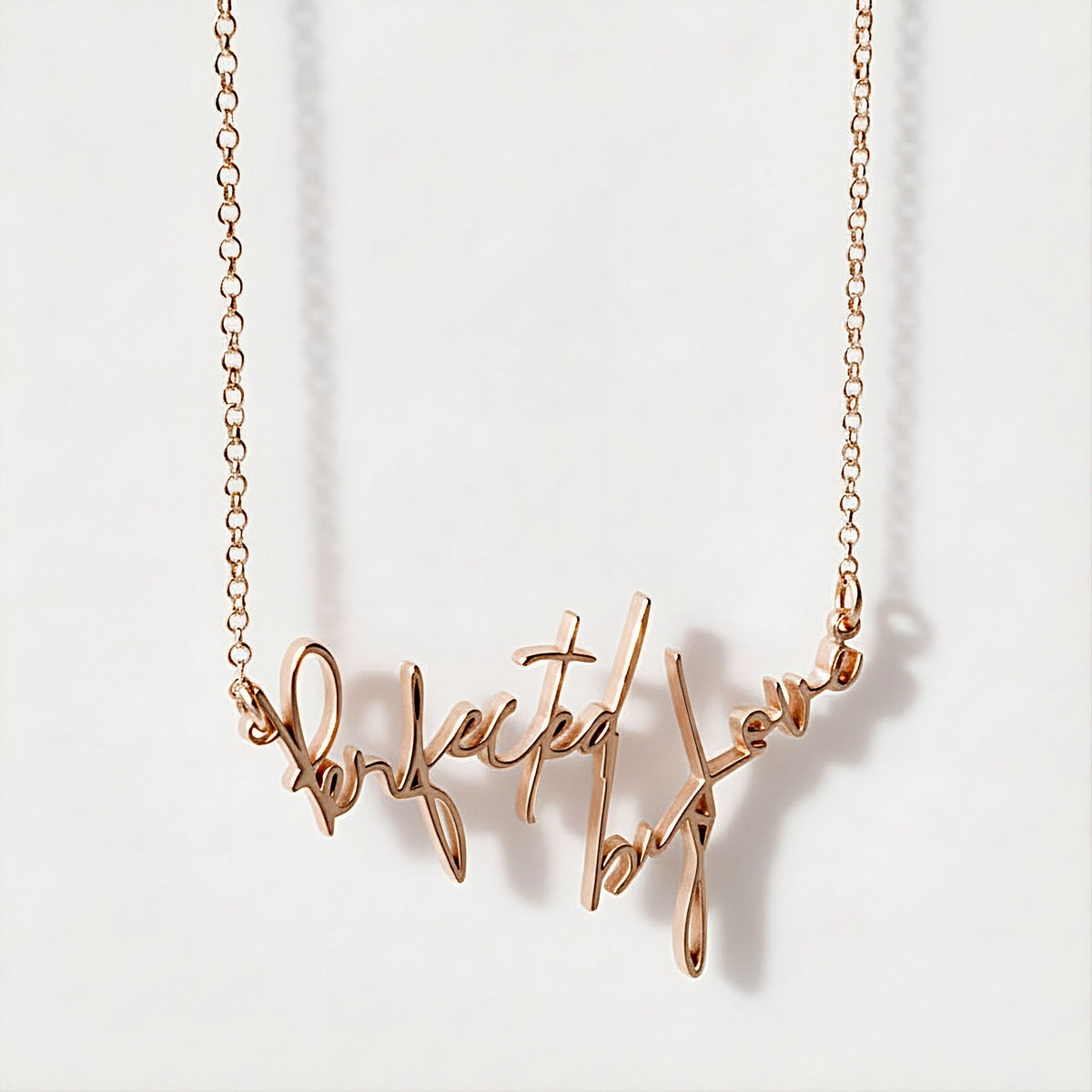 Close-up of the Perfected by Love affirmation pendant highlighting its polished 18K rose gold vermeil finish.