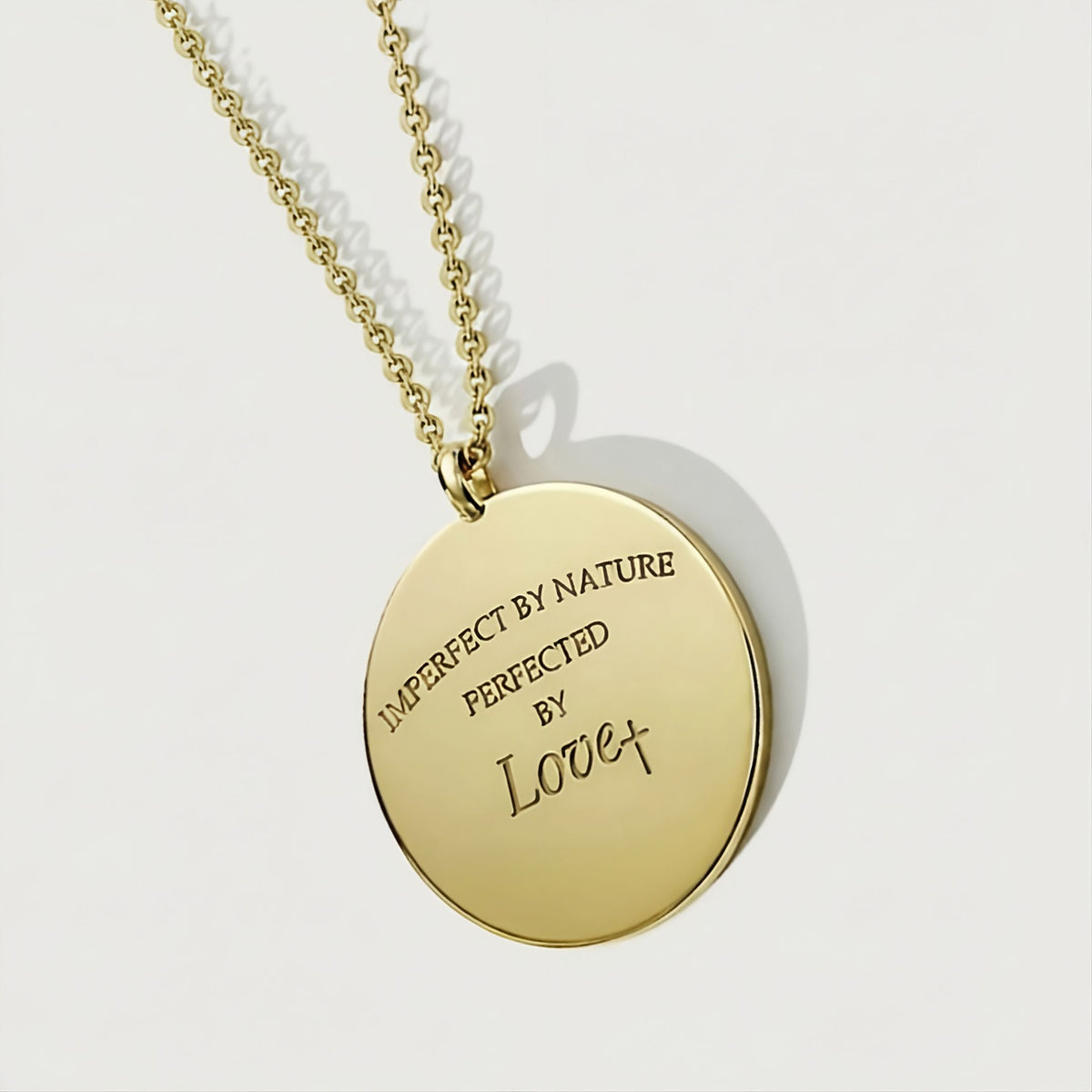 Close-up of the Perfected by Love solid 14K gold coin pendant highlighting its meaningful design and polished finish.