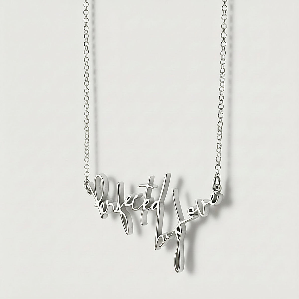 Close-up of the 2-inch Perfected by Love Sterling Silver affirmation pendant highlighting its polished finish.
