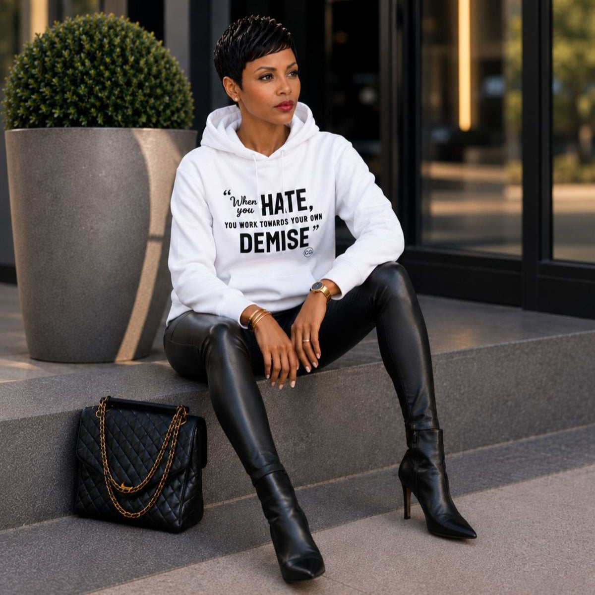 Woman wearing the Rachel's Worth Demise Hoodie featuring the When You Hate, You Work Towards Your Own Demise statement.