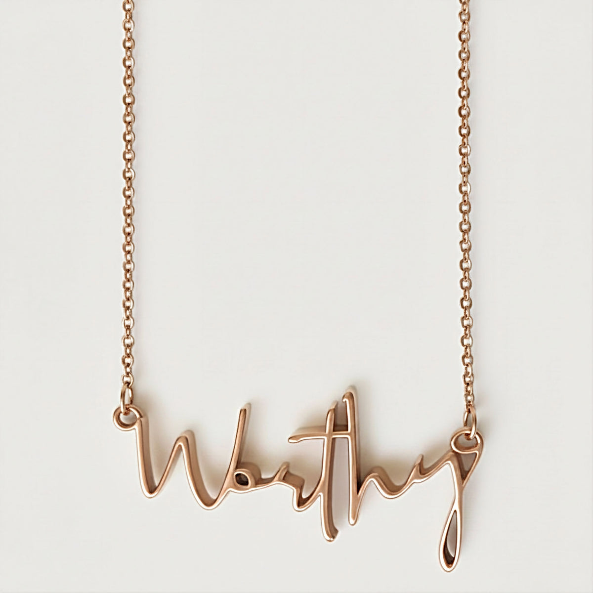 Front view of the Worthy 18K Rose Gold Vermeil Affirmation Necklace with its refined elongated pendant.