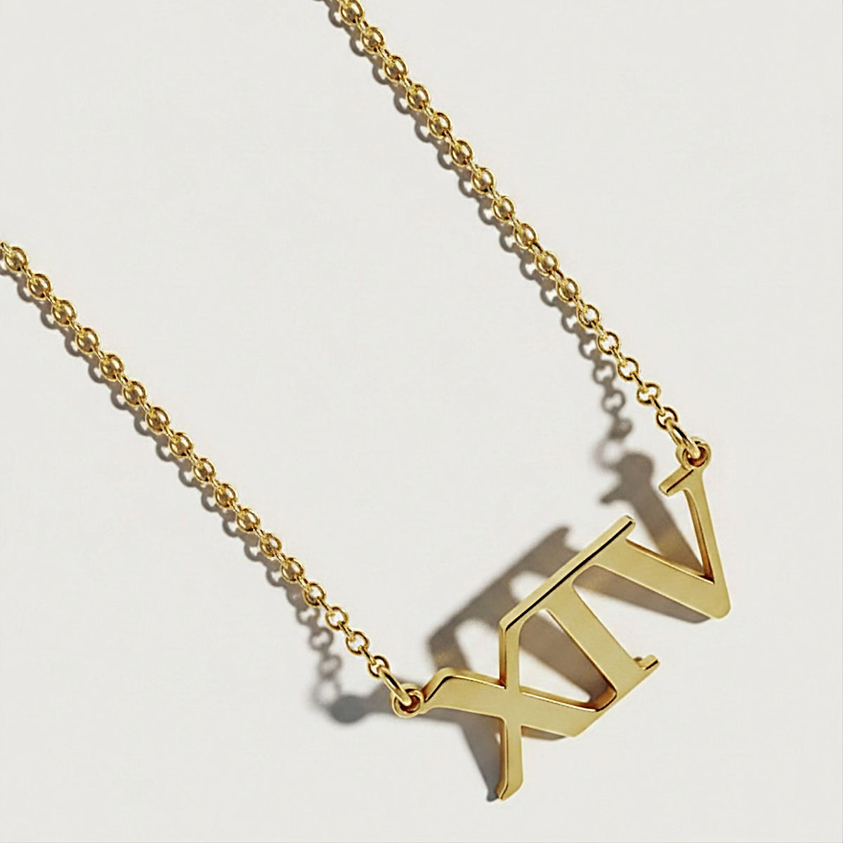 Close-up of the XIV pendant highlighting its polished 18K yellow gold vermeil finish.